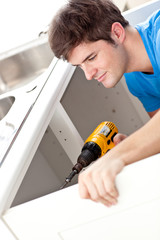Confident man holding a drill repairing a kitchen sink