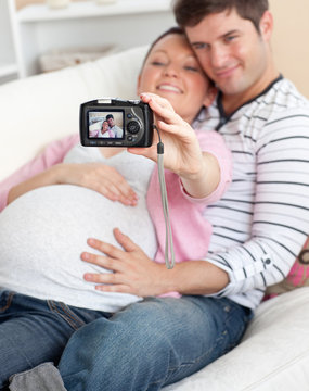 Close-up of a joyful pregnant woman and her husband taking pictu