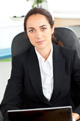 Self-assured hispanic businesswoman sitting at her desk in front