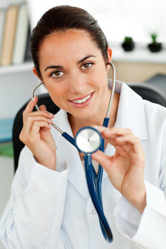 Assertive hispanic doctor holding a stethoscope at the camera