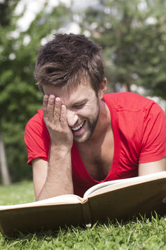 jeune homme riant lisant un livre d&eacute;lassement