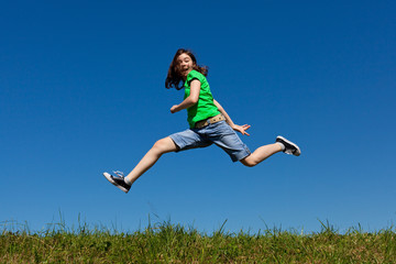 Girl jumping, running against blue sky