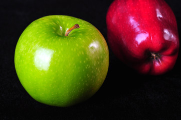 Green and red apples in exhibition, on a black background