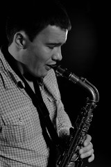 Fototapeta na wymiar Young handsome man playing music on saxophone. black background