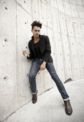 Attractive man dressed in jeans and boots in a grungy scenary