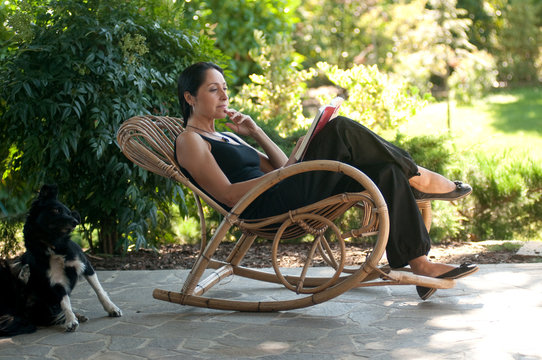 Donna legge su sedia a dondolo  in giardino