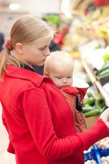 Young mother with baby daughter shopping in supermarket