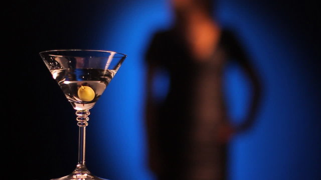 Olive falls in a glass of martini