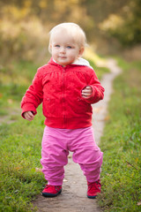 young adorable baby walking by the road in field near forest