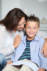 Obraz premium Little blond boy sitting on sofa with his mother