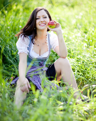 Junge Frau sitzt mit Apfel im Gras
