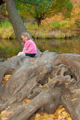 Girl looks back with smile. She is sitting near the pond