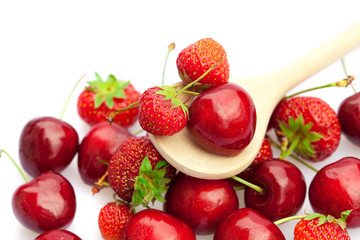 cherry in a spoon against a background of strawberries and cherr