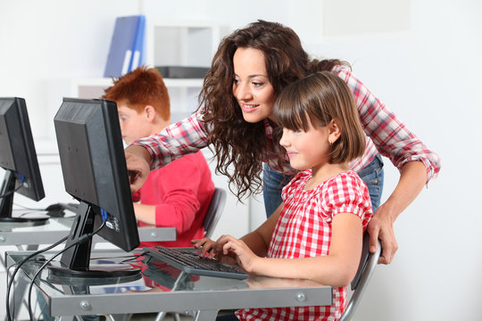 Teacher and children learning to use computer