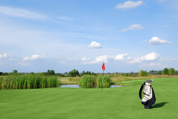 golf field with red flag and bag