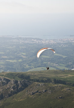 Paraglider man above Atlantic coast and little mountains