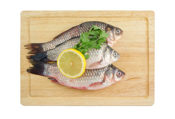 Raw crucians with lemon and parsley on cutting board isolated