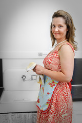 A woman in vintage clothing poses in the kitchen