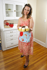 An attractive woman in vintage clothing with cupcakes