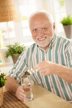 Portrait of senior man taking medicine at home