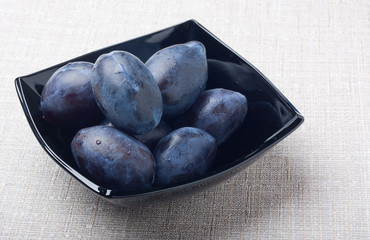 Black glass bowl with plums