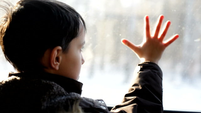 The boy looks out of the window. A train. The car. The railway.