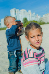 Pretty brother and sister playing with a camera on the street