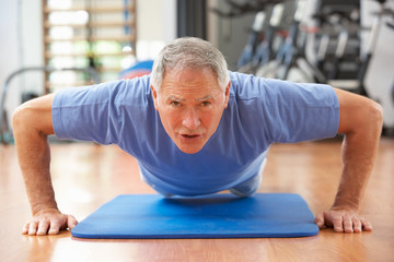 Fototapeta premium Senior Man Doing Press Ups In Gym
