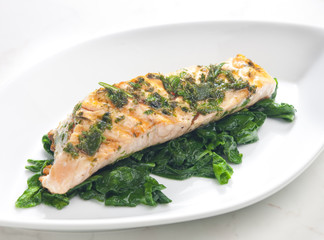 grilled salmon with herbs on fried spinach