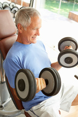 Fototapeta na wymiar Senior Man Working With Weights In Gym