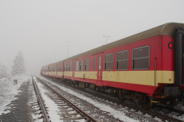 Fototapeta premium Red train in freezing weather with frozen trees and fog