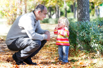 father and daughter looking at each other on autumn park backgro