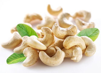 Ripe cashew nuts with leaves on a white background.
