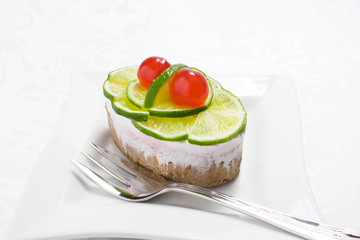 Sponge cake with whipped cream and slices of lime and cherry