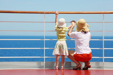 behind mother and her daughter standing on deck of yacht