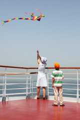 mother and son playing with multicolored kite on deck