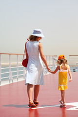 young mother and daughter walking on cruise liner deck