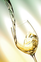 Pour white vine into glass with light background.