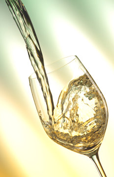 Fototapeta Pour white vine into glass with light background.