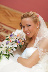 Wedding. Portrait of bride with bouquet in hands indoors.
