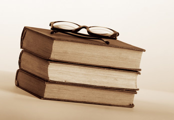 Three old book in pile with eyeglasses