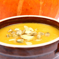Pumpkin soup with pumpkin seeds a pumpkin in the background
