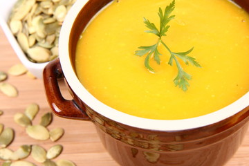 Pumpkin soup with parsley and pumpkin seeds on wood