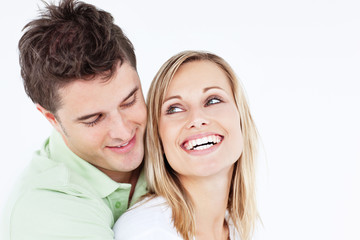 handsome man hugging his laughing girlfriend against a white bac