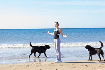 Pretty woman running with her dogs on the beach