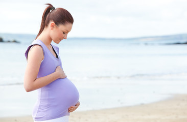 Pretty pregnant woman standing on the beach