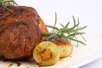 Roast pork with some onions and rosemary in close up