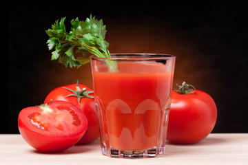 Fresh tomatoes and a glass full of tomato juice.