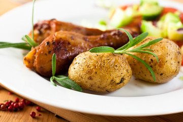 Baked potatoes and roast chicken with herbs