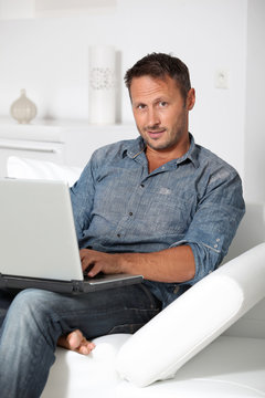 Man with laptop computer sitting in sofa